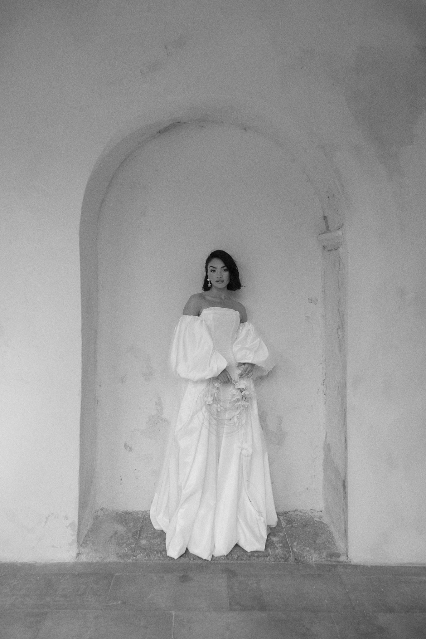 Bride standing inside a historic stone alcove during a wedding in Portugal