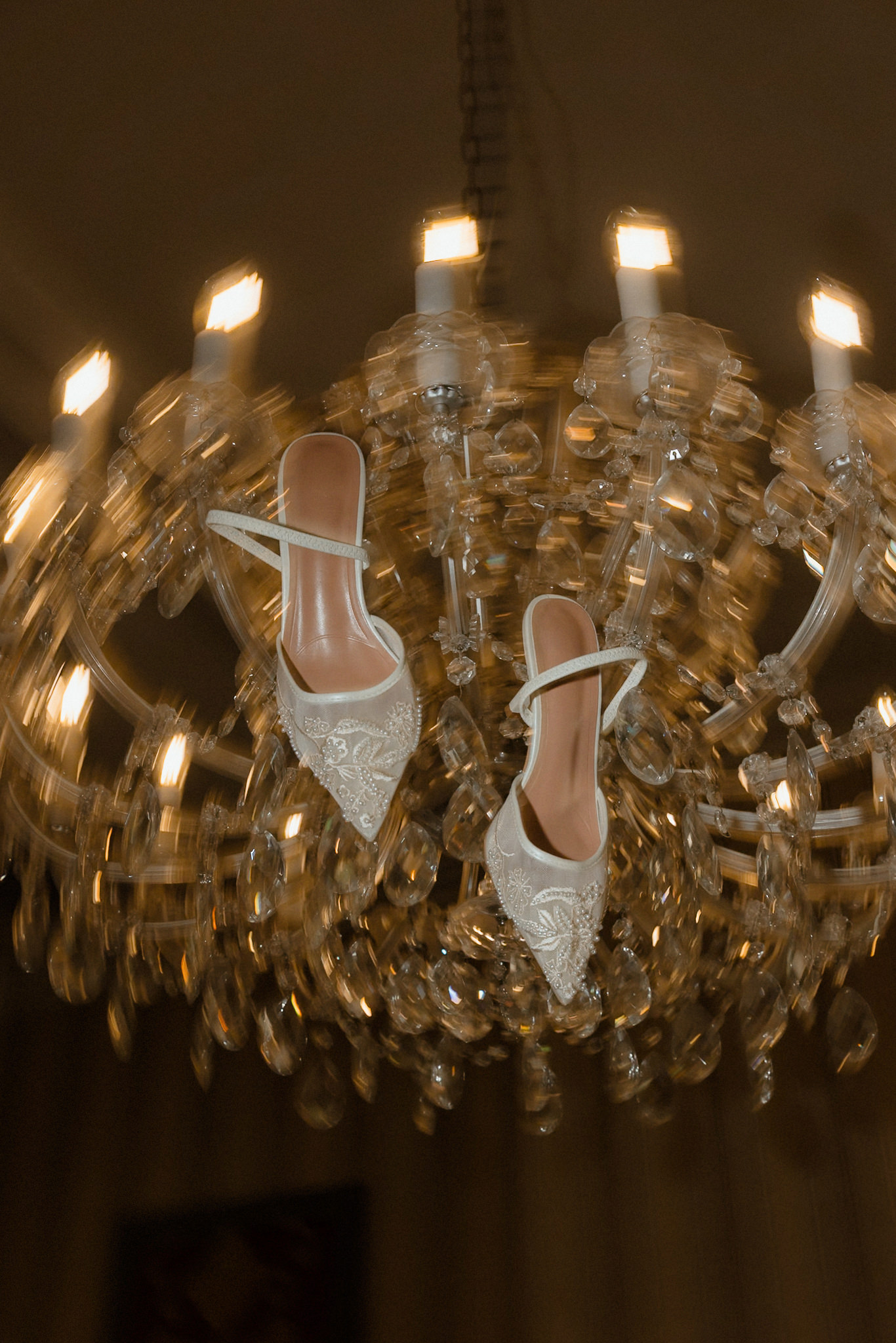 Bridal shoes displayed on a chandelier as part of the wedding details